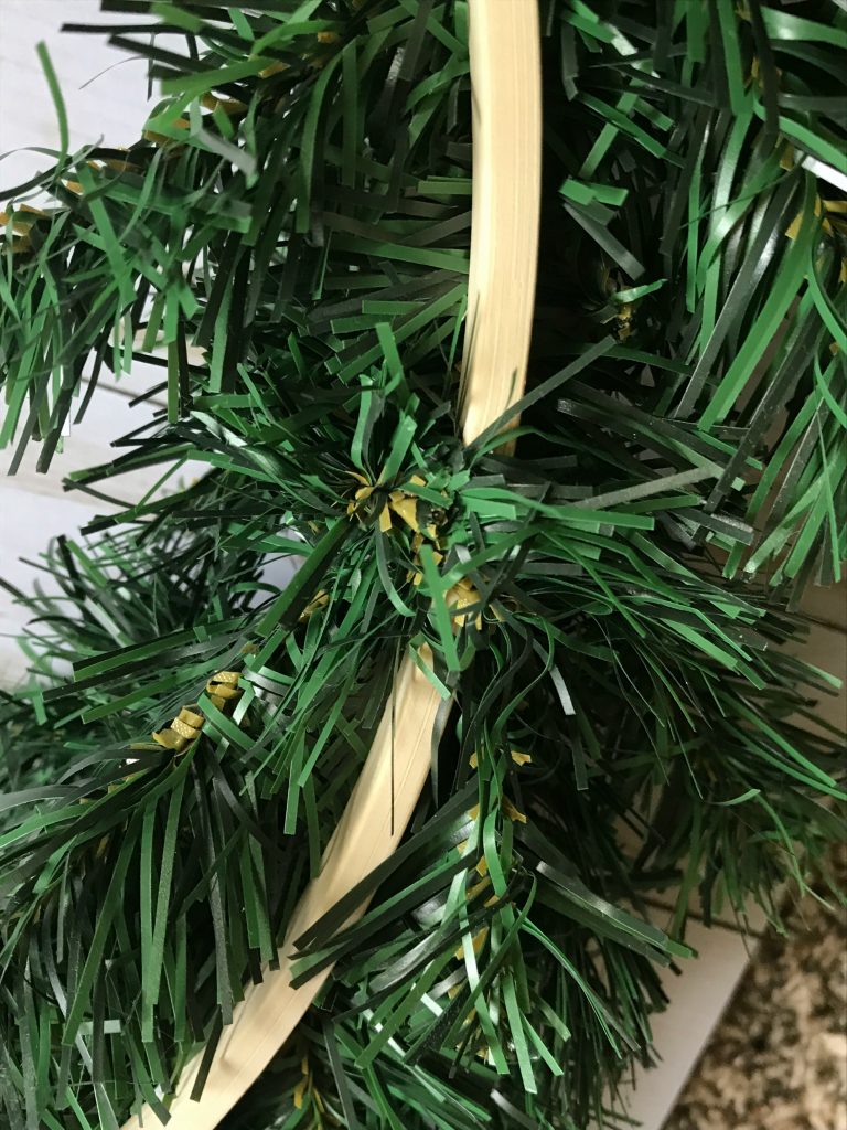 attach greenery garland to hoop by wrapping pieces of the garland around the hoop