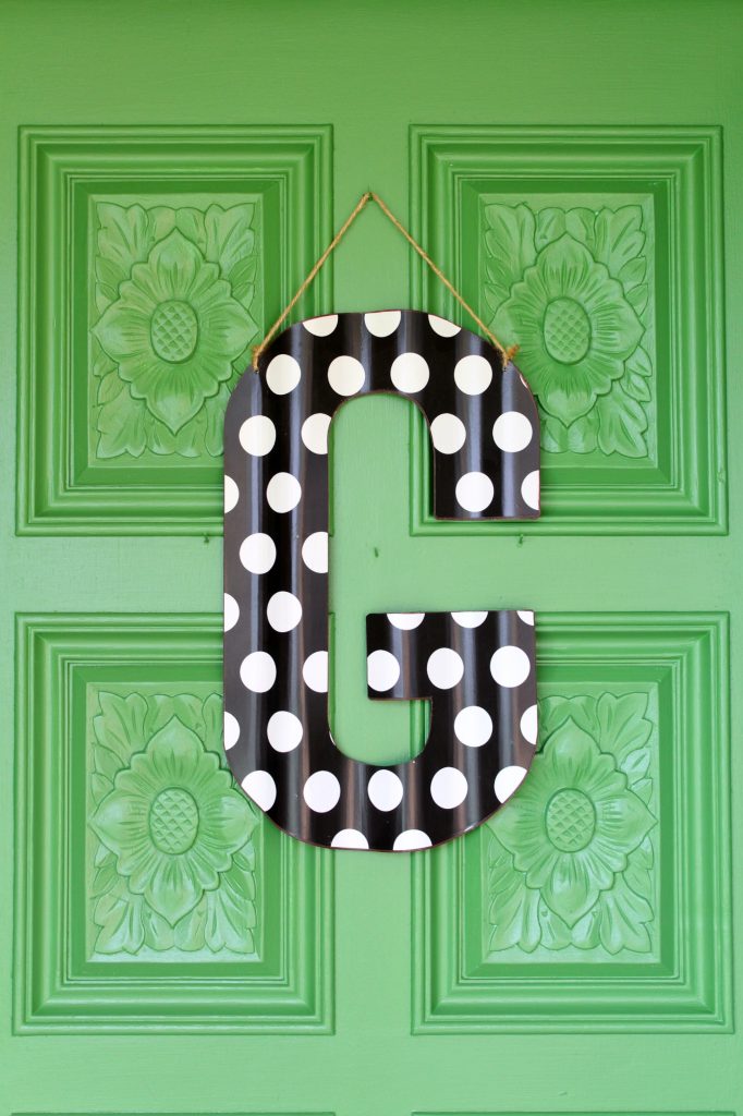 Green front door with large black and white polka dotted letter