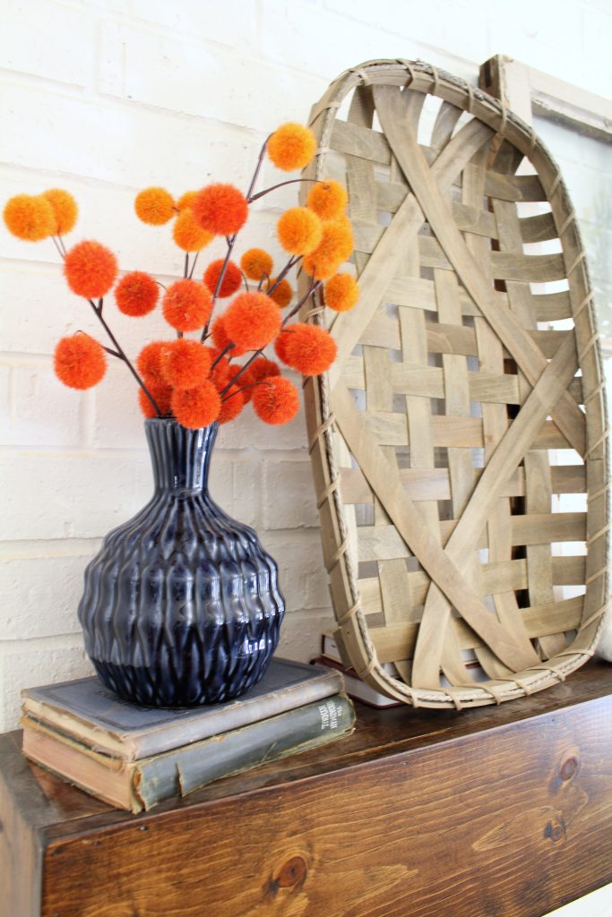 Orange poms and tobacco basket fall mantel decor