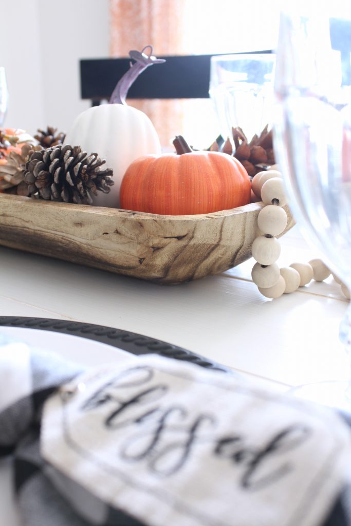 Wood trough filled with pumpkins and pine cones for fall centerpiece